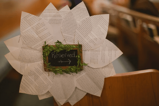 Reserved signs at a wedding are made in a flower shape with book pages.